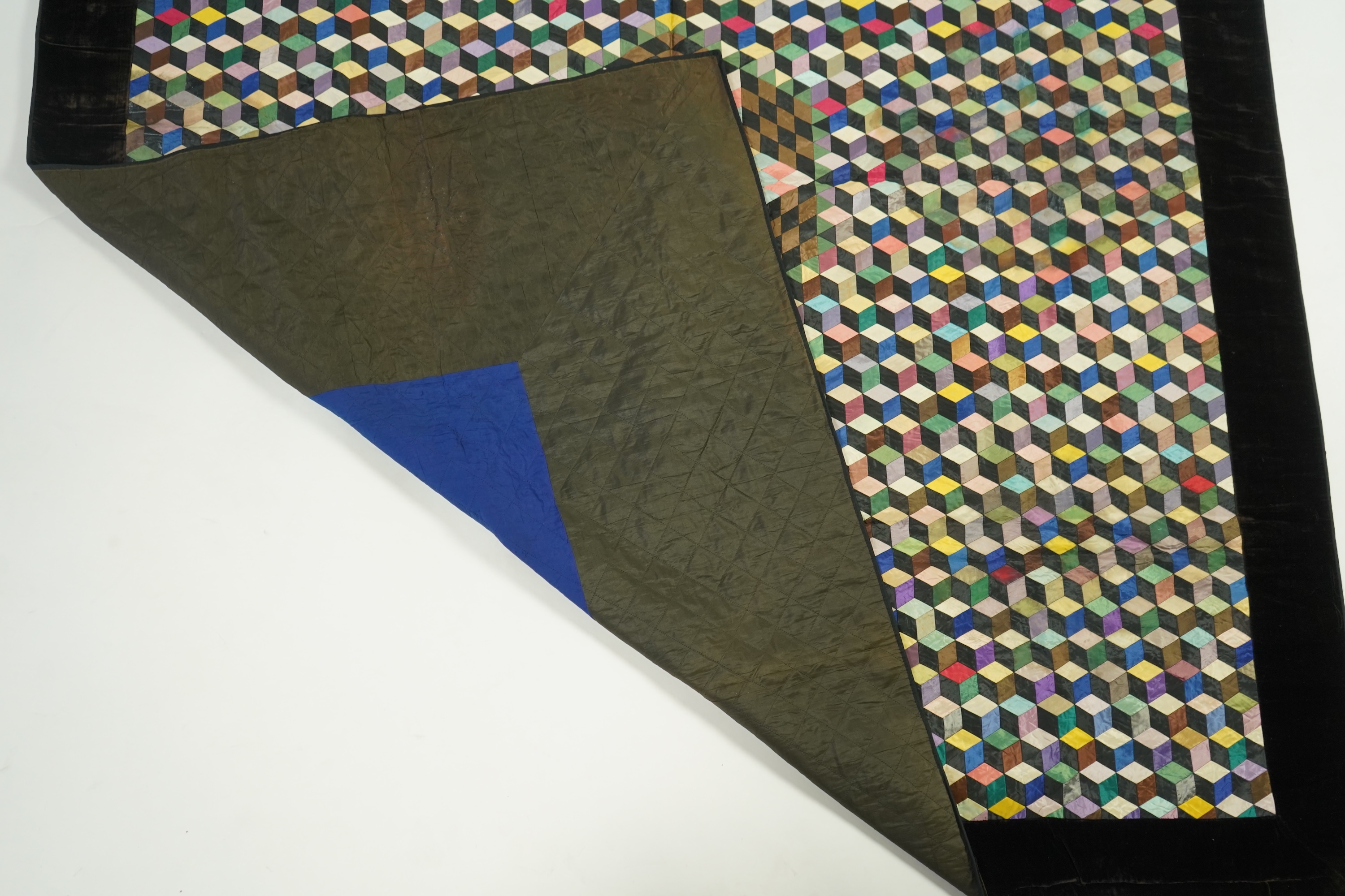 An English 19th century silk ‘Tumbling Blocks’, hand sewn, patchwork quilt, with central star motif and wide velvet border. Worked with multi coloured silks backed with black and blue silk., 170cm x 152cm. Condition - th